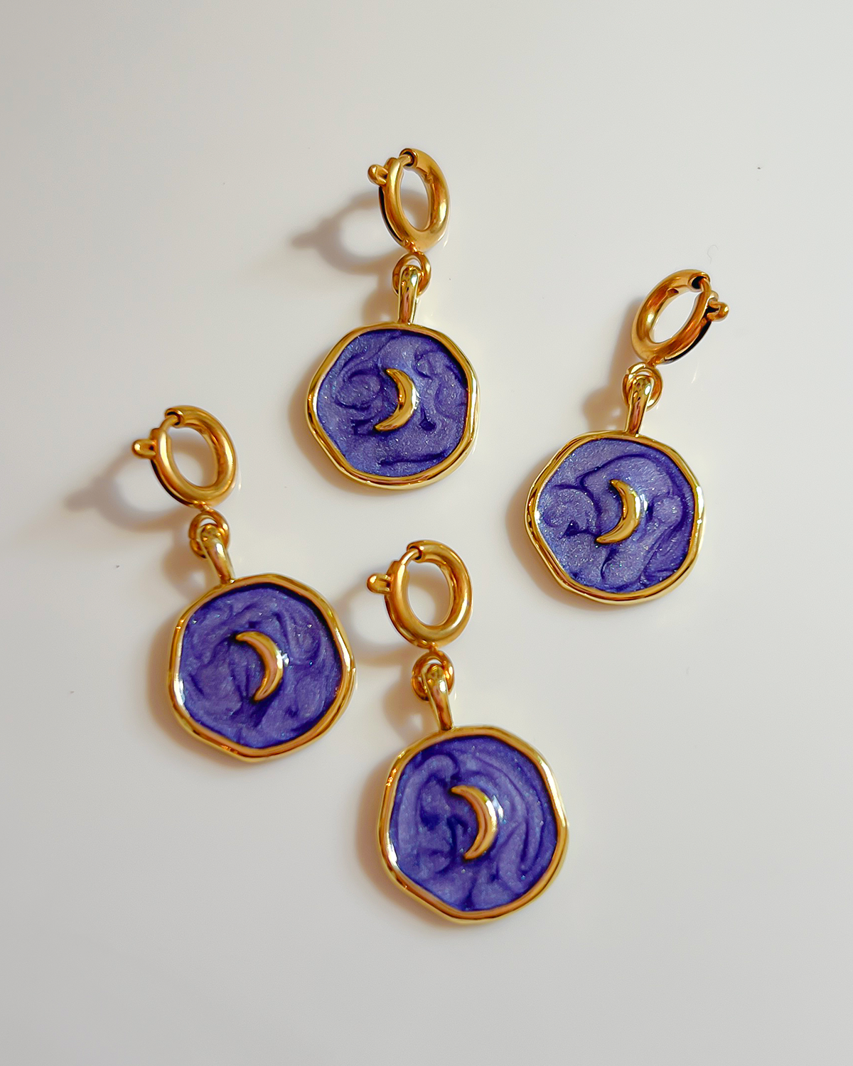 Set of purple charms with gold crescent moon designs on a white background