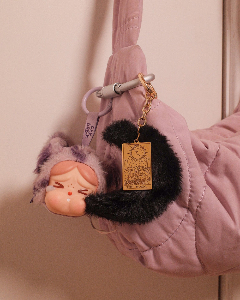 Fluffy moon keychain with tarot card charm attached to a pink jacket.