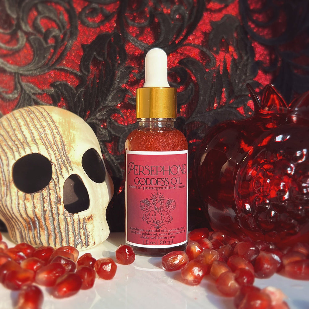 Persephone Goddess Oil bottle with skull and pomegranates on a dark background